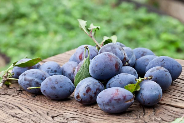 Plums on an old wooden table. — Stock Photo, Image