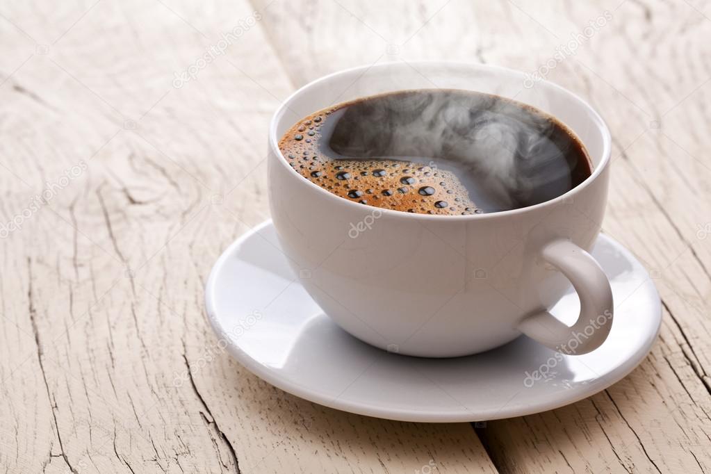 Cup of hot coffee on an old wooden table.