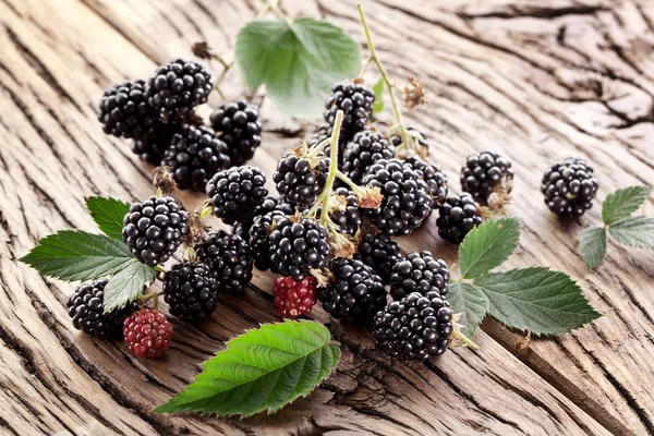 Blackberries with leaves on a old wooden table. — Stock Photo, Image