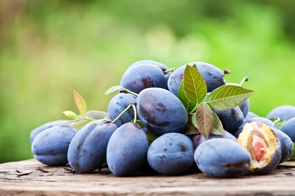 Plums on an old wooden table. — Stock Photo, Image