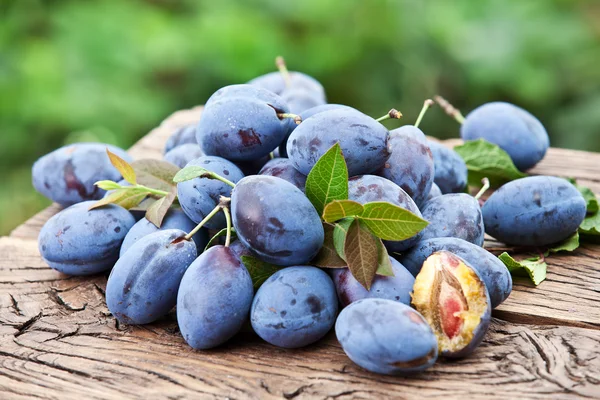 Plums on an old wooden table. — Stock Photo, Image