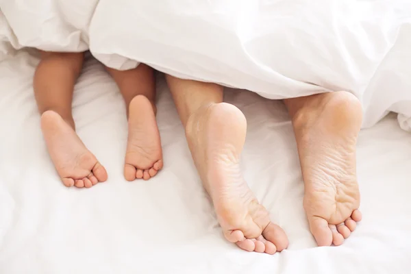 Erwachsenen- und Babyfüße unter der Decke. — Stockfoto