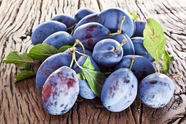 Plums on an old wooden table. — Stock Photo, Image