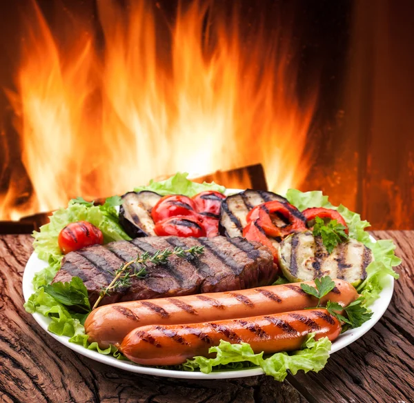 Grillen: steak, korv och grönsaker på en tallrik. — Stockfoto