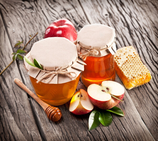 Glass cans full of honey, apples and combs.