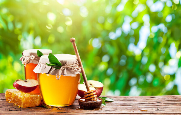 Glass cans full of honey, apple and combs.