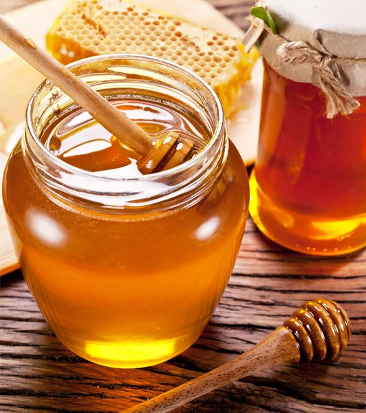 Wooden dripper in glass can full of honey on wooden table. — Stock Photo, Image