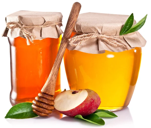 Latas de vidrio llenas de miel, pedazo de manzana y tarro de miel en whi — Foto de Stock