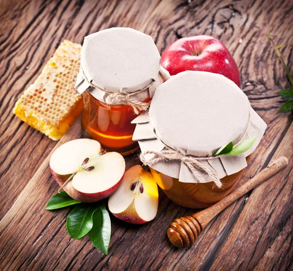 Glass cans full of honey and apples and combs. — Stock Photo, Image