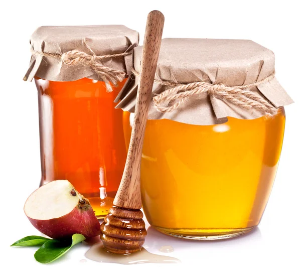 Glass can full of honey, piece of apples and wooden dipper. Stock Photo