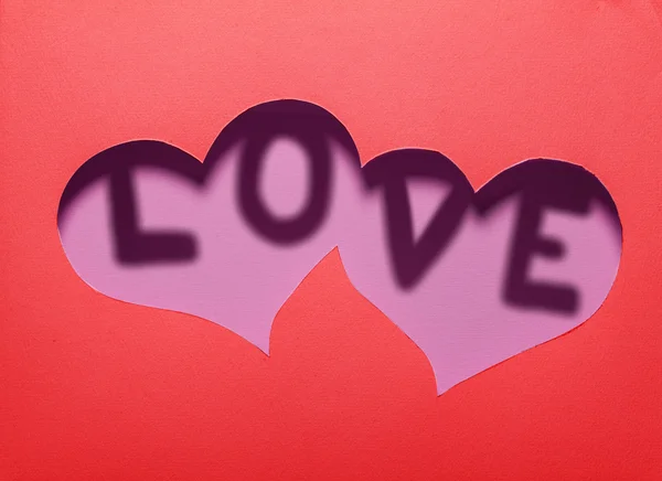 Two hearts cutout in red paper with word "LOVE" inside. — Stock Photo, Image