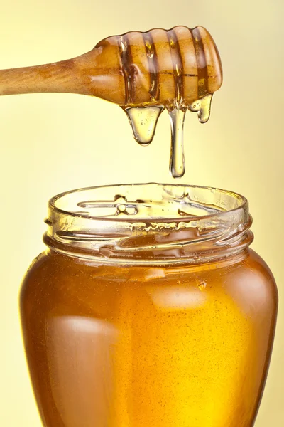 Honey droplets flowing from wooden stick. — Stock Photo, Image