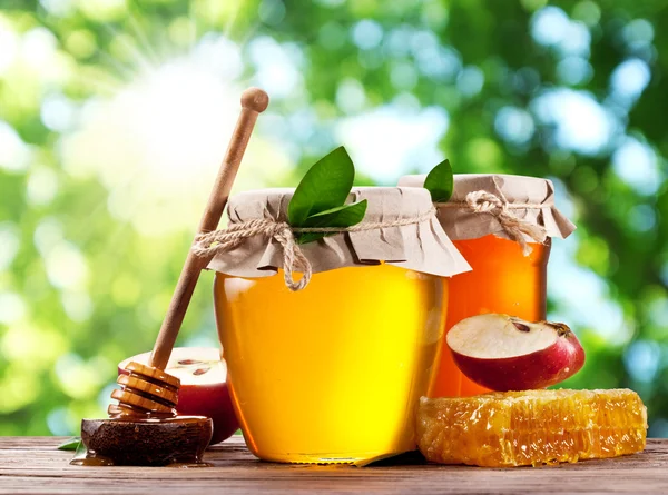 Glass cans full of honey, apple and combs on wood. — Stock Photo, Image