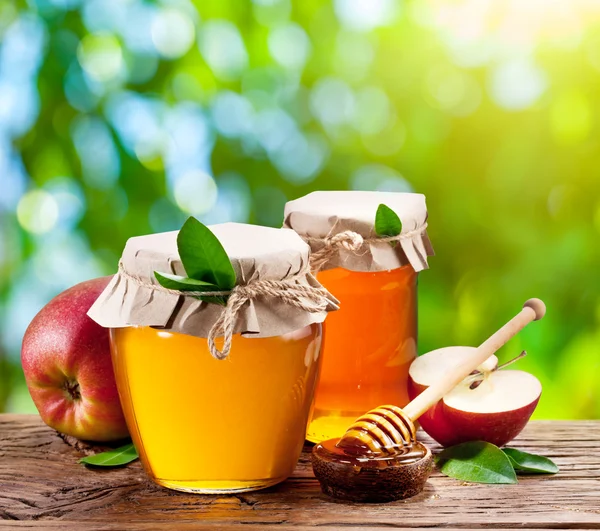 Glass cans full of honey, apples and combs. — Stock Photo, Image