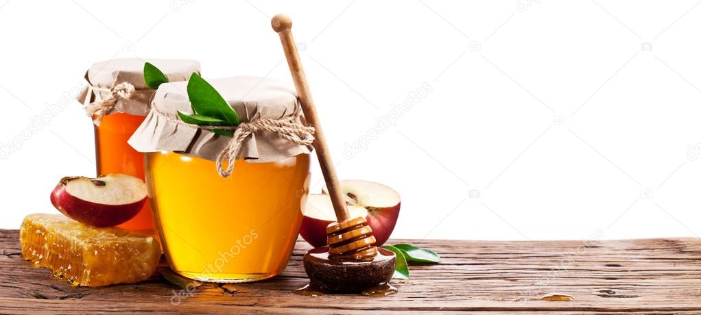 Glass can full of honey, apples and honeycombs on old wooden tab