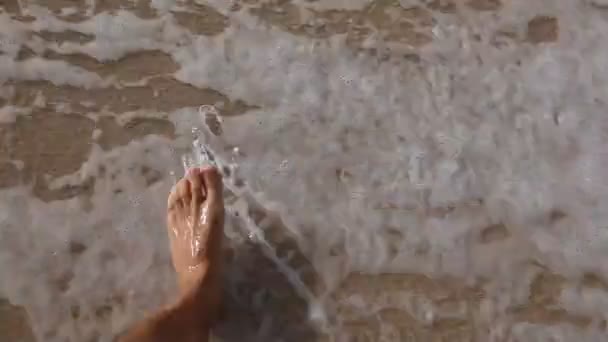 Uomo a piedi nudi sulla spiaggia di sabbia in onda oceanica, punto di vista . — Video Stock