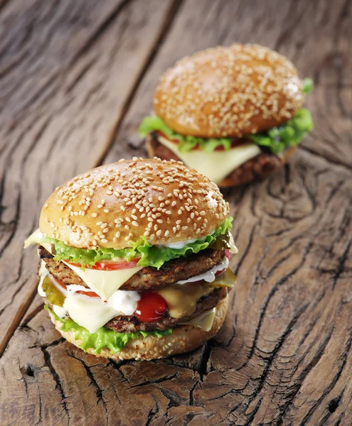 Deux hamburgers sur une vieille table en bois . — Photo