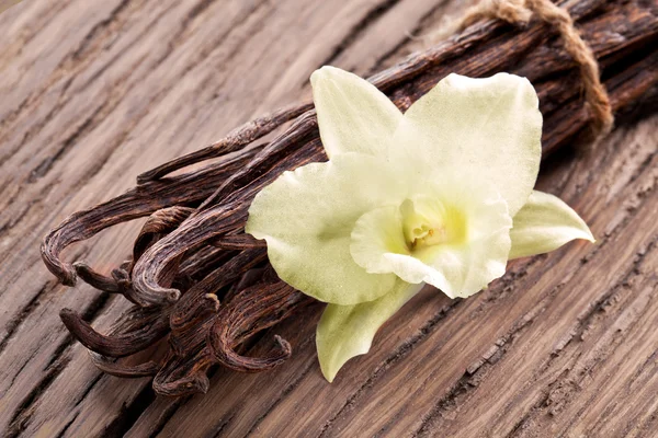 Mazzo di bastoncini di vaniglia e fiori su legno vecchio . — Foto Stock