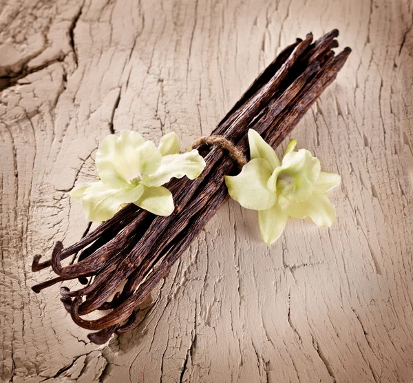 Bunch of vanilla sticks and flowers on old wood. — Stock Photo, Image