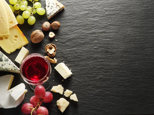 Different types of cheeses with wine glass and fruits. — Stock Photo, Image