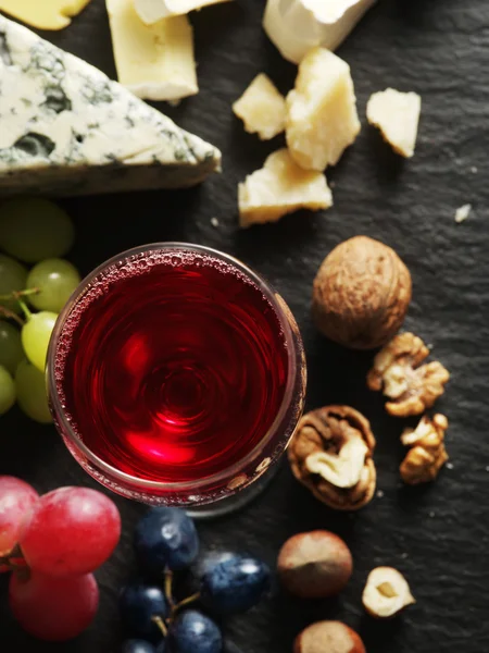 Verschillende soorten kazen met glas wijn en fruit. — Stockfoto