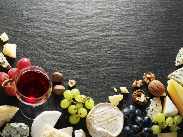 Diferentes tipos de queijos com copo de vinho e frutas . — Fotografia de Stock