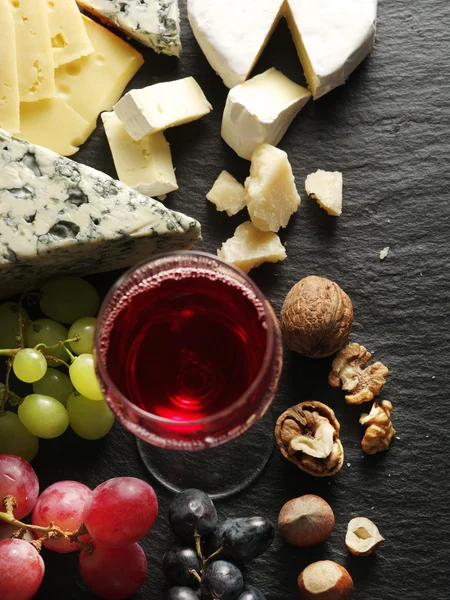 Verschillende soorten kazen met glas wijn en fruit. — Stockfoto