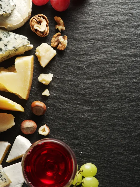 Verschillende soorten kazen met glas wijn en fruit. — Stockfoto