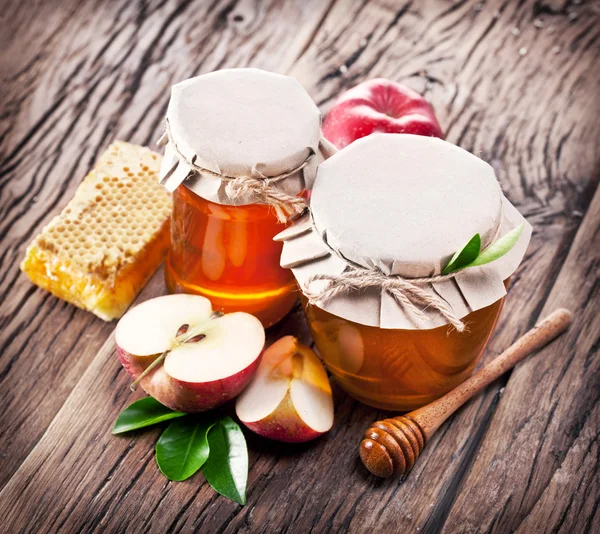 Glass cans full of honey, apples honeycombs on wood. — Stock Photo, Image