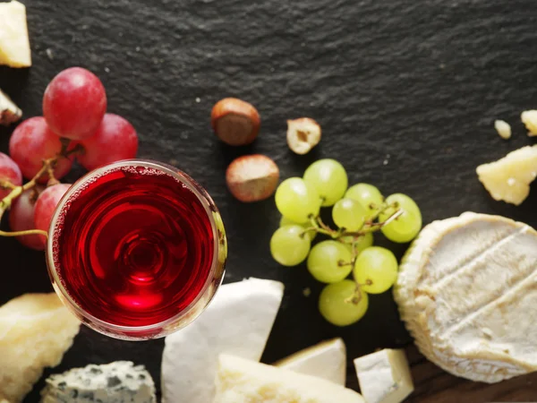 Verschillende soorten kazen met glas wijn en fruit. — Stockfoto