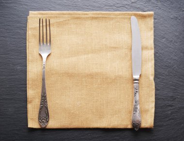 Koyu gri arka plan üzerinde gümüş çatal bıçak takımı.