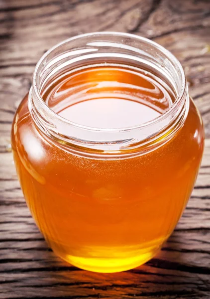 Glass can full of honey on wooden table. — Stock Photo, Image