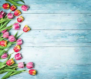 Ahşap bir zemin üzerine pembe ve kırmızı laleler.