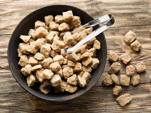 Cubes of cane sugar in the bowl on wooden table. — Free Stock Photo