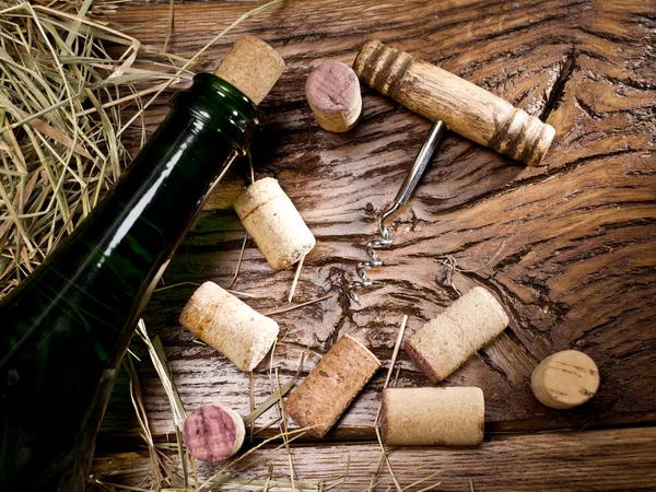 Botella de vino y corchos en una vieja mesa de madera . — Foto de Stock