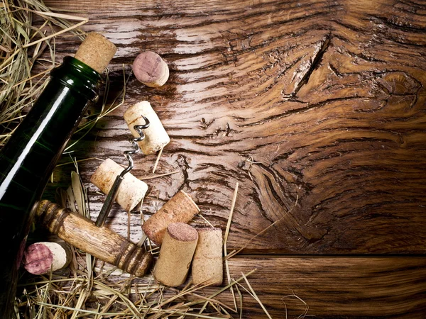 Butelka wina i korki na starym drewnianym stole. — Zdjęcie stockowe