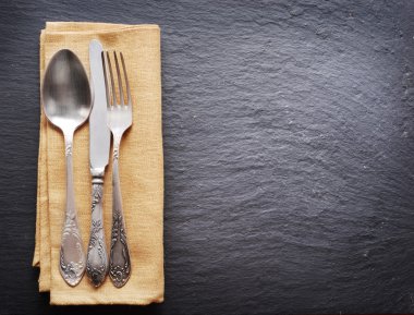 Koyu gri arka plan üzerinde gümüş çatal bıçak takımı.