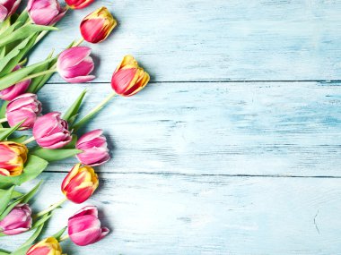 Ahşap bir zemin üzerine pembe ve kırmızı laleler.