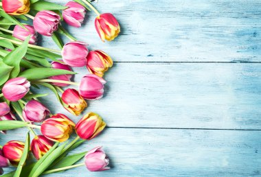 Ahşap bir zemin üzerine pembe ve kırmızı laleler.