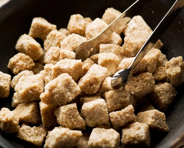 Potongan gula tebu dalam mangkuk di atas meja kayu . — Stok Foto