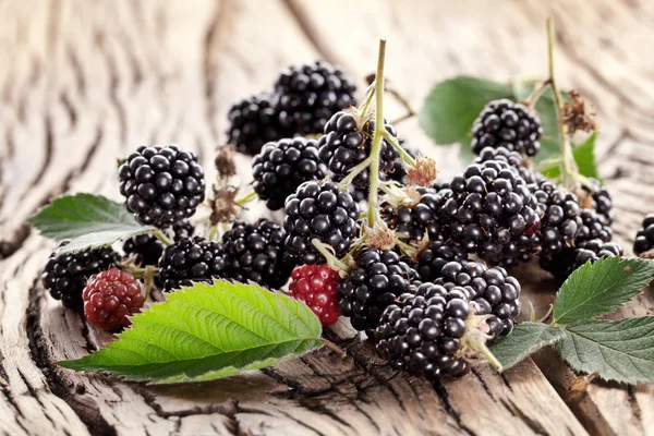 Blackberries with leaves on a old wooden table. — Stock Photo, Image
