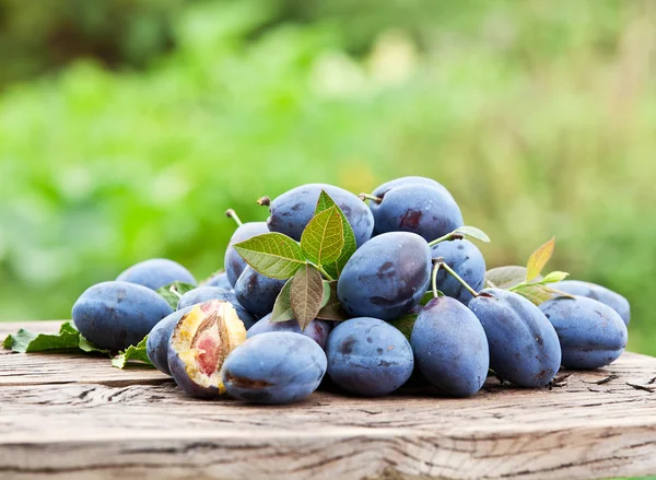 Plums on an old wooden table. — Stock Photo, Image