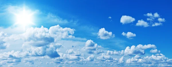 Nuvens brancas heap e sol brilhante no céu azul . — Fotografia de Stock