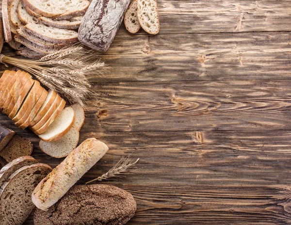 Chleb i pszenicy na drewniane biurko. — Zdjęcie stockowe