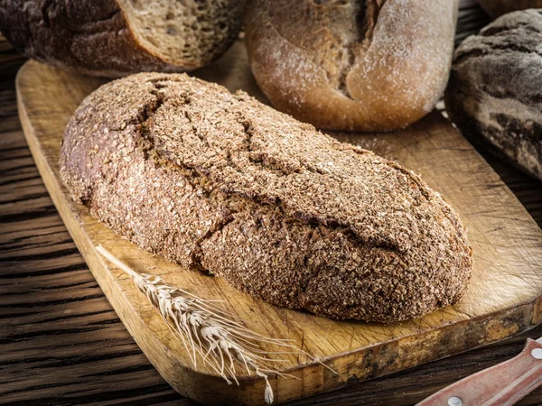 Lange zwarte brood op de houten plank. — Stockfoto