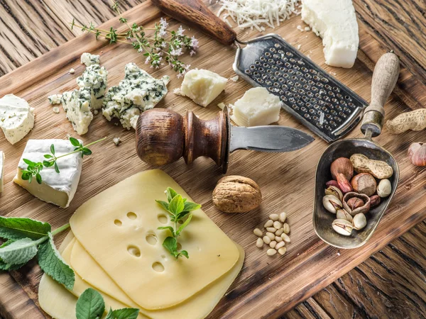 Different types of cheeses with nuts and herbs. — Stock Photo, Image