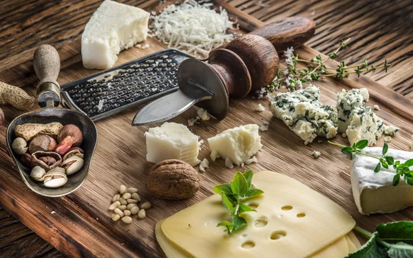 Different types of cheeses with nuts and herbs. — Stock Photo, Image