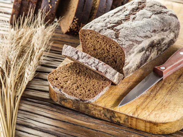 Skivad svart bröd på plankan. — Stockfoto