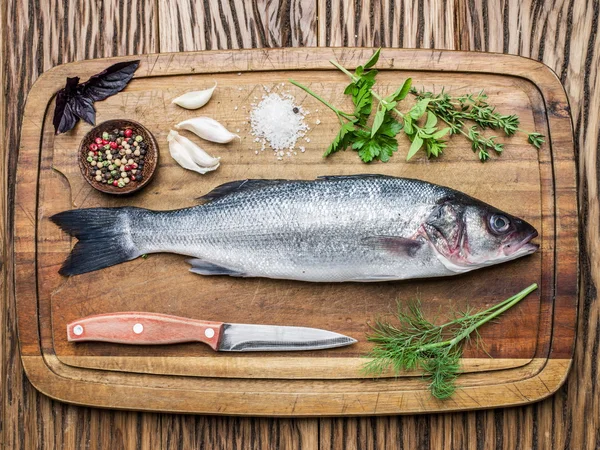 Seabass sur une planche en bois avec épices et herbes . — Photo