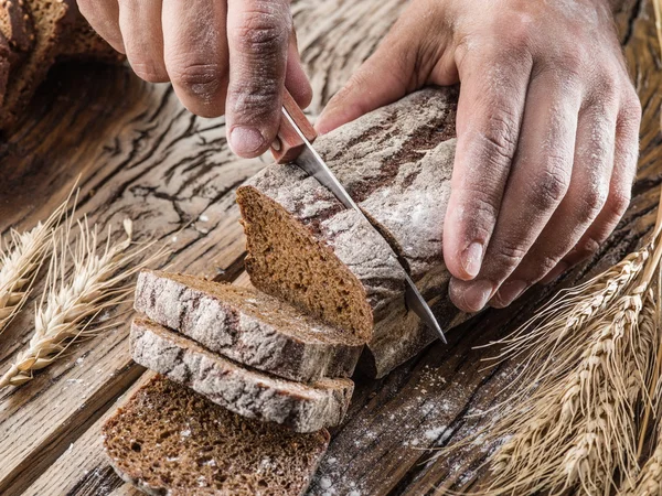 Menschenhände schnitten Brot auf. — Stockfoto